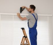 A male installing venetian blinds